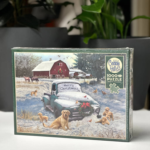 Cobble Hill puzzle box with a winter scene featuring a truck, dogs, and a barn.