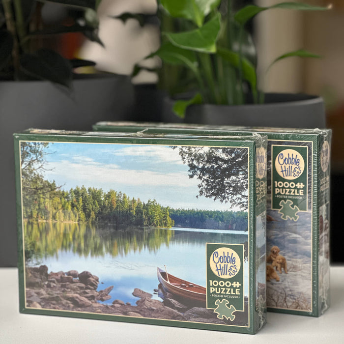 Cobble Hills puzzle box with a scenic design of a lake and boat, placed on a surface with a blurred indoor background.