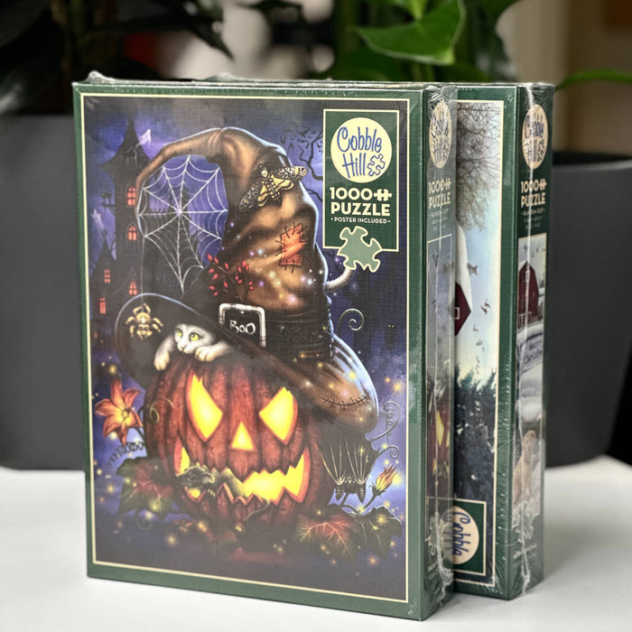 Two Halloween-themed puzzle boxes by Cobble Hill on a white surface with a blurred background.