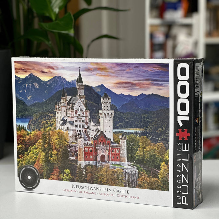 Jigsaw puzzle box featuring Neuschwanstein Castle with mountains and trees in the background.