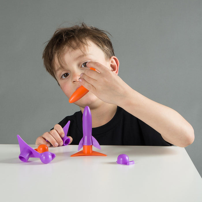 Child playing with toy rocket from heebie jeebies on a gray background