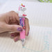 Hand holding a pink cartoon unicorn pen over a notebook