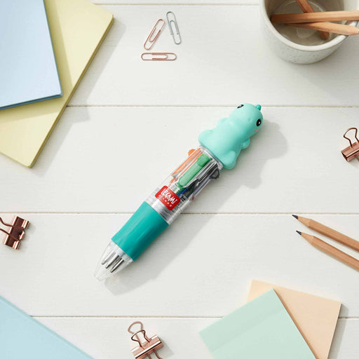 Mini 4-Colour Pen Dino Turquoise gel pen with cartoon character on a desk with stationery items