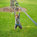 Child playing on a rope ladder in a grassy area