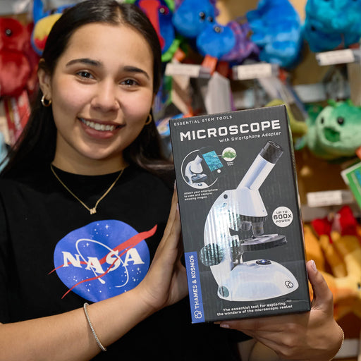 Person holding a microscope packaging with a NASA shirt in the background