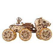 NASA-themed mechanical models packaging on a wooden surface Wooden model of a vehicle with large wheels on a white background