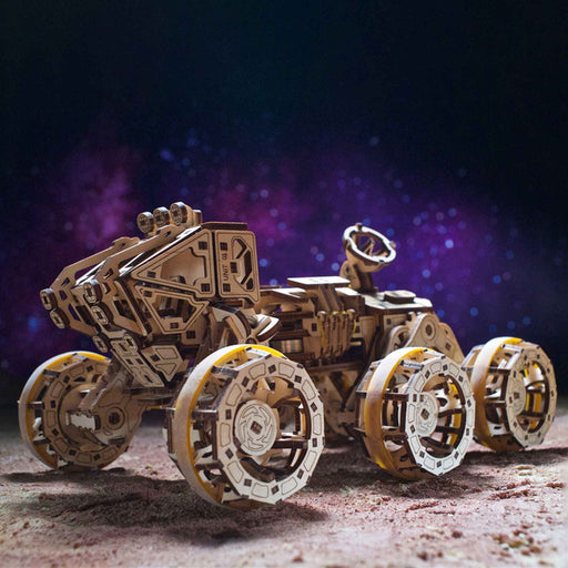 NASA-themed mechanical models packaging on a wooden surface Wooden mechanical model of a vehicle on a dark background