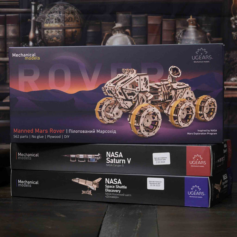 NASA-themed mechanical models packaging on a wooden surface Boxed mechanical model of a Mars rover with UGears branding on a dark background.