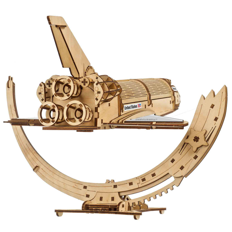 NASA-themed mechanical models packaging on a wooden surface Wooden model kit of a rocket ship on a white background