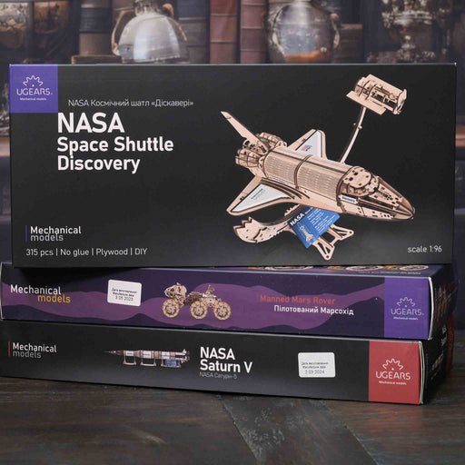 NASA-themed mechanical models packaging on a wooden surface