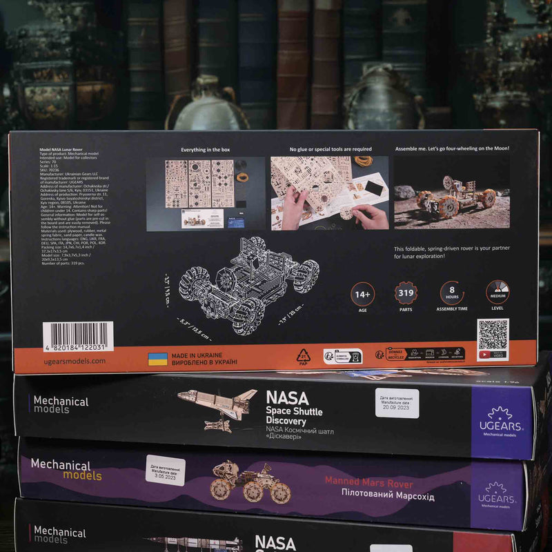 UGears NASA mechanical model Stack of NASA-themed model kit boxes with detailed illustrations on a reflective surface.