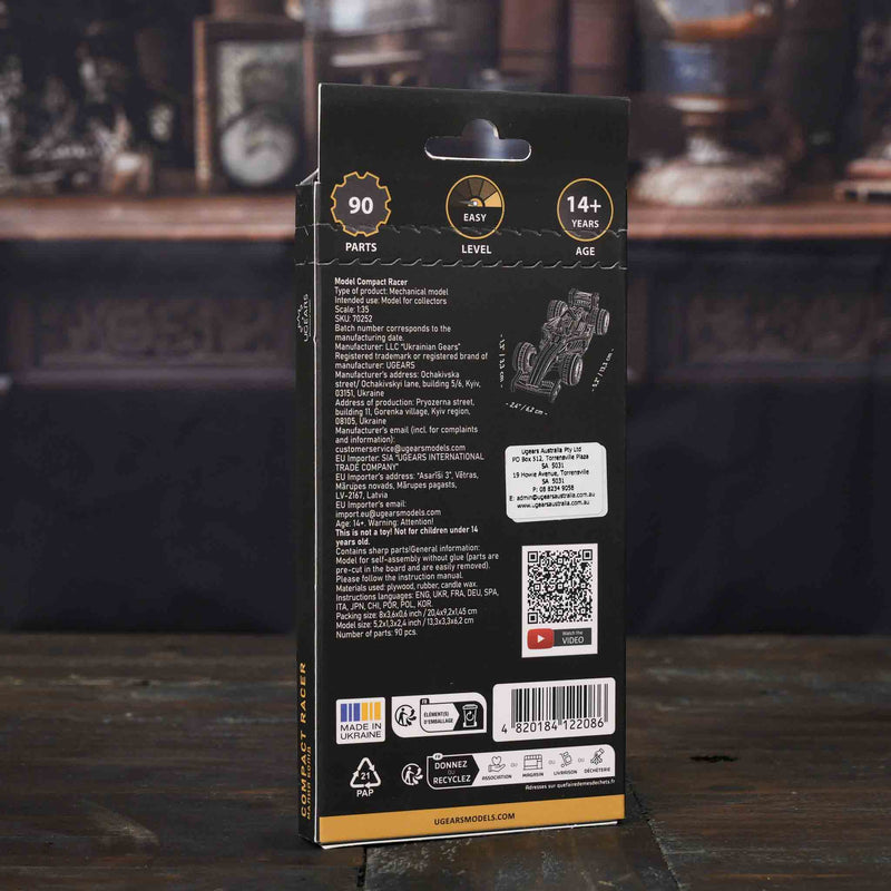 Ugears Compact Racer model Back view of a model kit packaging with text and graphics on a wooden surface.