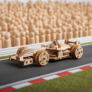 Ugears Compact Racer model Wooden model of a race car on a miniature racetrack with wooden stands in the background.