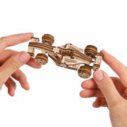 Ugears Compact Racer model Wooden model car being held by two hands against a white background