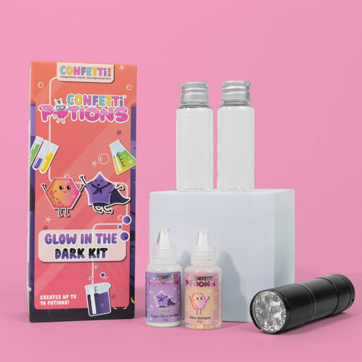 Glow in the dark kit with packaging, bottles, and a flashlight on a pink background