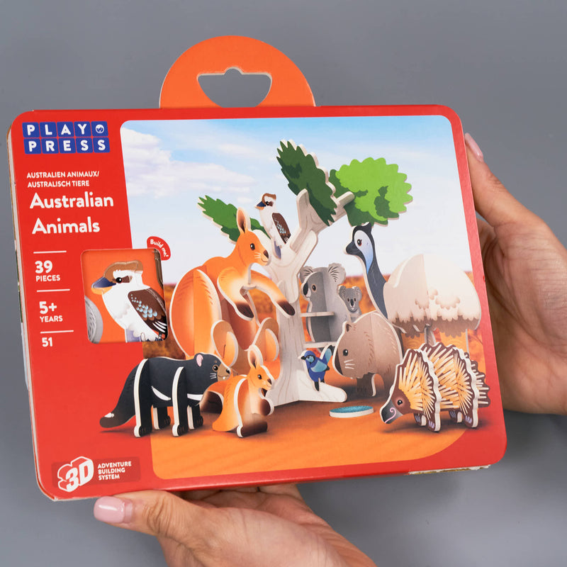 Packaging of a toy set featuring Australian animals with a hand holding it.