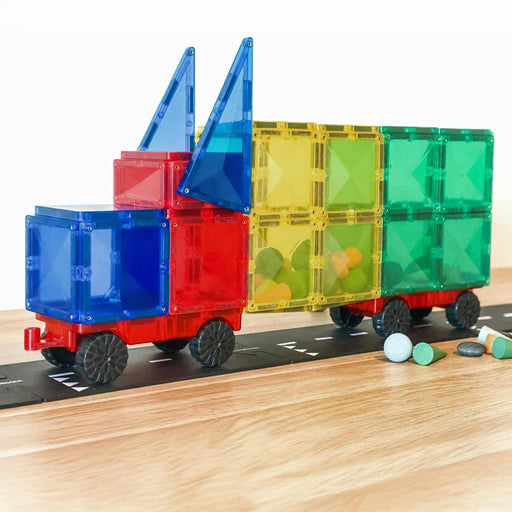 Colorful toy truck made connetix board of transparent plastic blocks on a wooden surface with a white background Connetix magnetic tiles