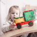 Child playing with a colorful toy truck on a wooden surface Connetix magnetic tiles