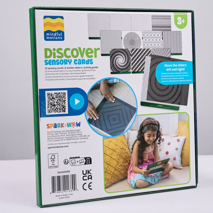 The retail packaging of the 'Discover Sensory Cards' activity kit by Mindful Motions and Sparkwax. The box features a white background with green borders, displaying various sensory card designs, age suitability information, and a lifestyle photo of a young girl playing with the cards on a sofa.