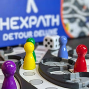 Board game with colorful player pieces and a 'HEXPath Detour Deluxe' logo in the background.