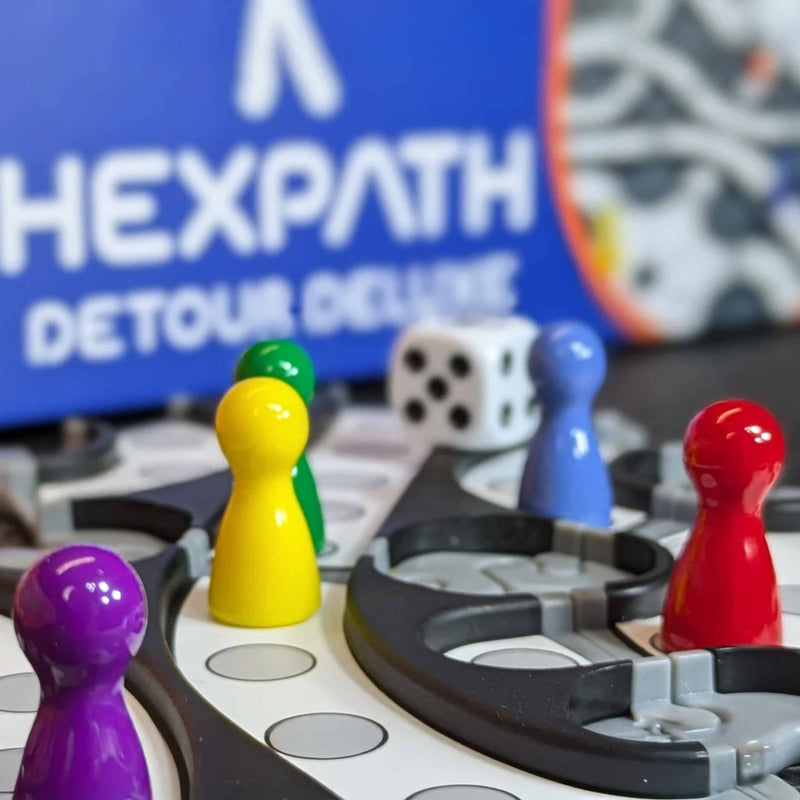 Board game with colorful player pieces and a 'HEXPath Detour Deluxe' logo in the background.
