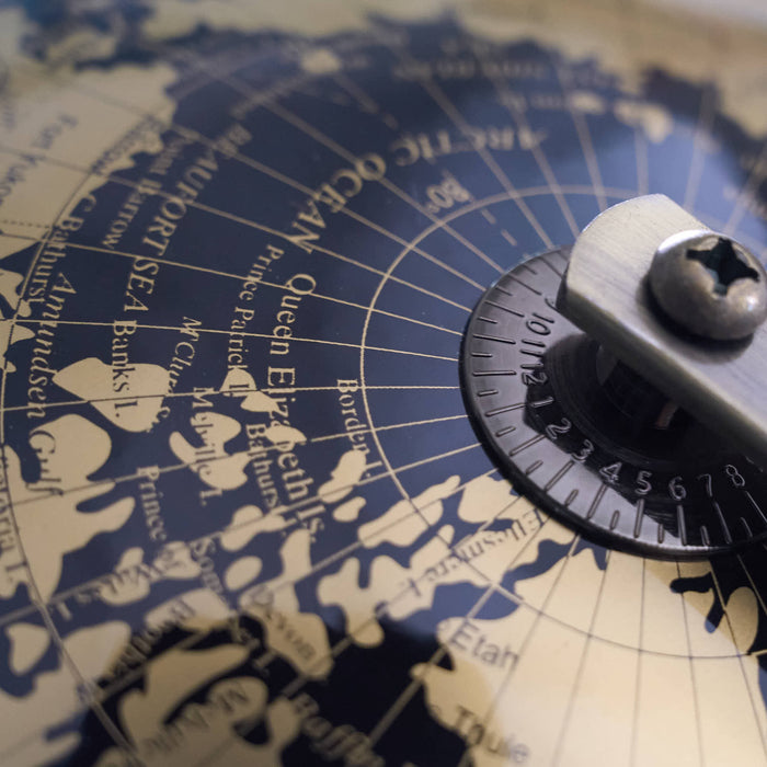 Vintage-style globe map with a compass rose on a wooden surface