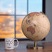 Globe and mug on a desk with a blurred window background