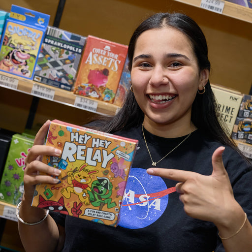 Person holding a 'Hey Hey Relay' game box in a store setting