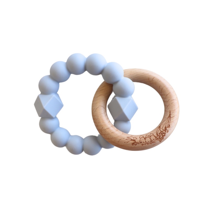 A blue teething toy consisting of a silicone ring and a beech wood ring with a patterned design.