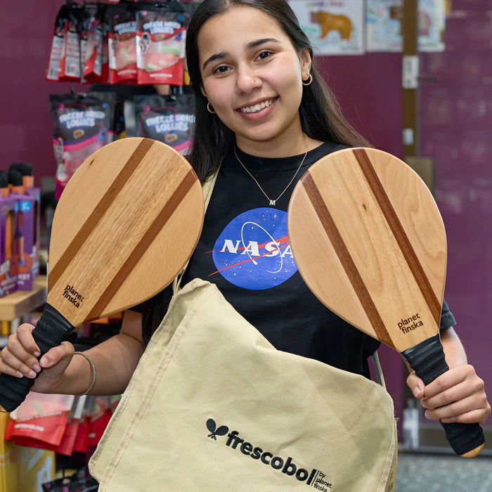 Person holding two wooden paddle sports products with a NASA shirt in a store setting