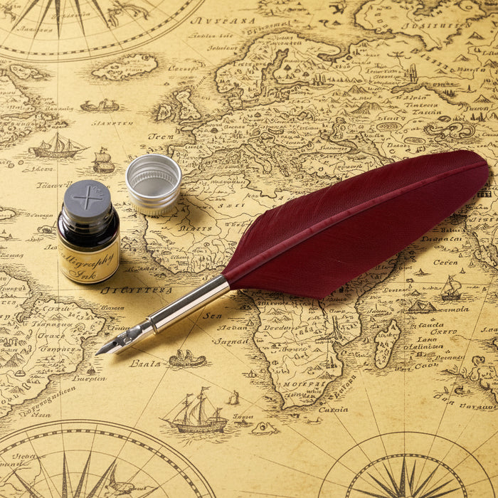 Red feather quill pen with ink bottle and inkwell