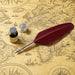 Red feather quill pen with ink bottle and inkwell