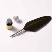 Feather quill pen with ink bottle and inkwell on a white background