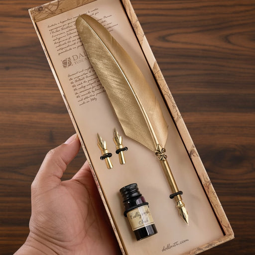 Gold feather quill pen set with ink bottle in a decorative box on a wooden surface