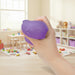 Hand holding a purple bear-shaped stress ball in a classroom setting