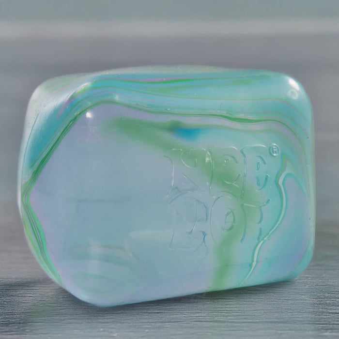 Marbled green and blue cube swirl needoh on a gray surface