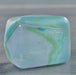 Marbled green and blue cube swirl needoh on a gray surface