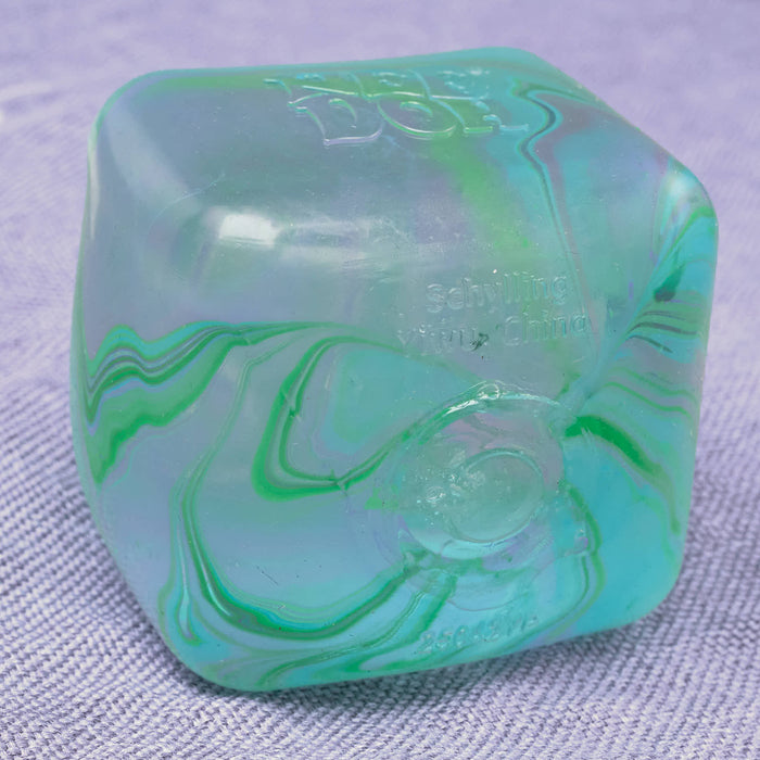 Marbled green and blue cube swirl needoh object on a textured gray background