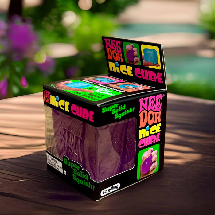 Box of Nee Doh Nice Cube on a wooden surface with a blurred outdoor background