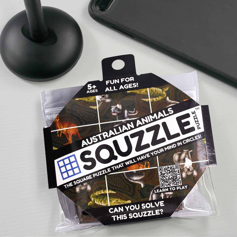 Squzzle Australian Animals puzzle packaging on a light gray surface with a black stand and phone in the background.
