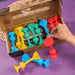 Cardboard packaging of TOSSIT product with colorful elements and text. Colorful dog toys with a cardboard box on a purple background