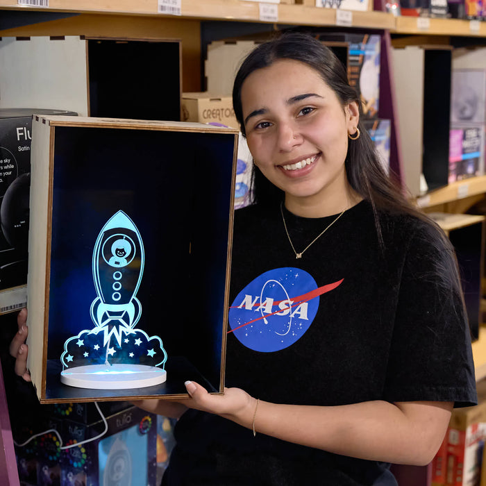 Person holding a framed artwork of a rocket with a NASA logo on their shirt.