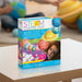 STEAM Powered Kids Solar System String Lights toy box displayed on a white table in a blurred indoor setting with children playing in the background.