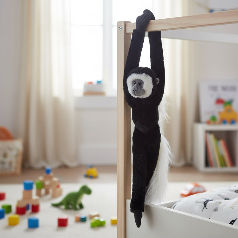 Black monkey toy hanging from a crib in a child's room with toys on the floor.