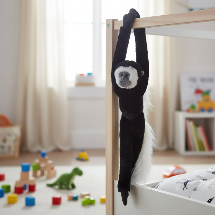 Black monkey toy hanging from a crib in a child's room with toys on the floor.