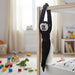 Black monkey toy hanging from a crib in a child's room with toys on the floor.