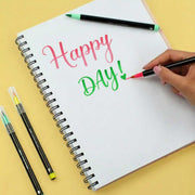 Notebook with 'Happy Day!' text being written with colorful pens on a yellow background