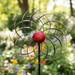 Decorative metal windmill with a red center on a white background