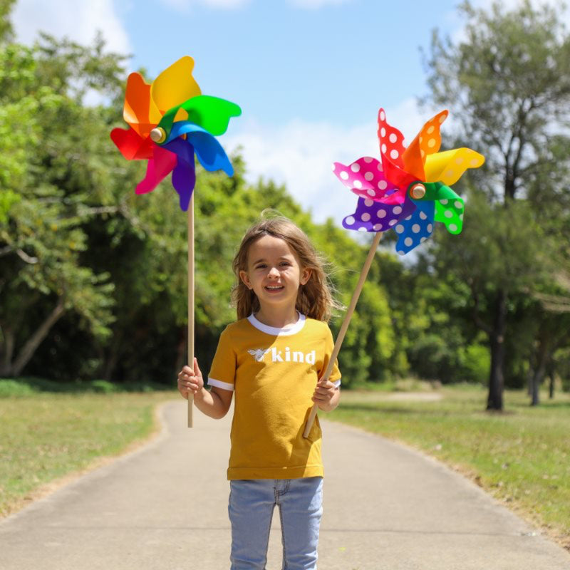 Child holding colorful pinwheels in a park