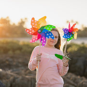 Child holding colorful pinwheels in a natural setting with a blurred background